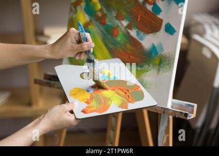 Peintre féminin tenir la palette et le pinceau mélangeant des peintures acryliques Banque D'Images