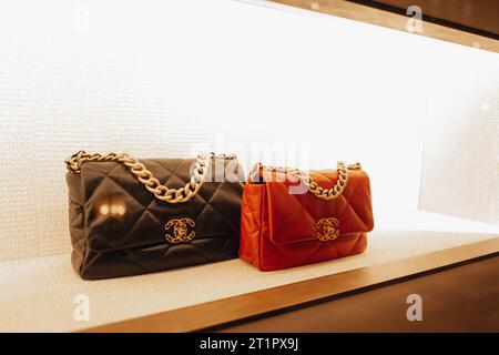 Sacs à main Chanel féminins orange chic rouge et noir avec chaîne dorée dans la fenêtre d'un magasin de luxe. Chanel est une marque de haute couture fondée par Coco C. Banque D'Images