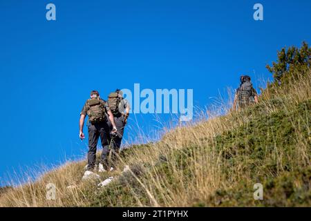 Les randonneurs avec des sacs à dos sur les épaules remontent la montagne. Ciel bleu en arrière-plan. Banque D'Images