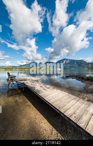 Nuages dérivant sur une passerelle en bois sur la rive du lac Kochelsee devant un paysage montagneux automnal et nuages dans le ciel, Bavière Banque D'Images