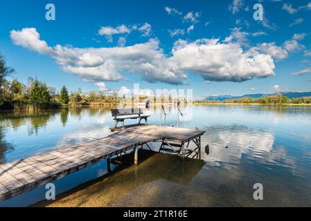 Nuages dérivant sur une passerelle en bois sur la rive du lac Kochelsee devant un paysage montagneux automnal et nuages dans le ciel, Bavière Banque D'Images