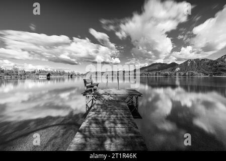 Nuages dérivant sur une passerelle en bois sur la rive du lac Kochelsee devant un paysage montagneux automnal et nuages dans le ciel, Bavière Banque D'Images