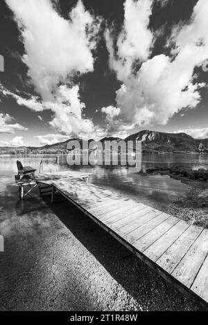 Nuages dérivant sur une passerelle en bois sur la rive du lac Kochelsee devant un paysage montagneux automnal et nuages dans le ciel, Bavière Banque D'Images