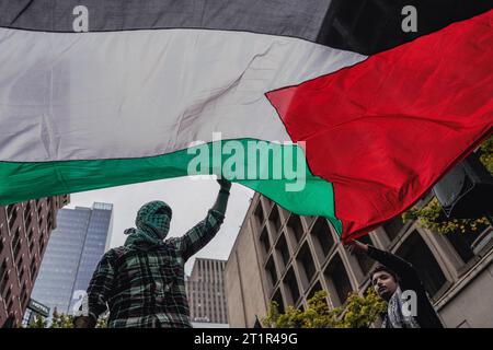 ÉTATS-UNIS. 14 octobre 2023. Les manifestants brandissent un drapeau pendant la manifestation. Des milliers de manifestants se sont rassemblés samedi à Westlake Park, dans le centre-ville de Seattle, pour exprimer leur opposition à de nouvelles violences à la suite des récentes attaques meurtrières qui ont pris Israël par surprise il y a à peine une semaine. La manifestation visait à réorienter l'attention vers le rétablissement des droits humains et la fourniture d'une aide humanitaire à la région déchirée par la guerre de Gaza. Cet événement est venu en réponse à l'incident tragique qui s'est produit le 7 octobre, lorsque des combattants armés associés au groupe militaire palestinien Hamas ont infiltré Israël, resulle Banque D'Images