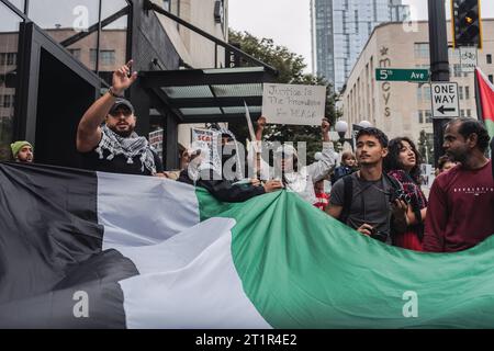 ÉTATS-UNIS. 14 octobre 2023. Les manifestants brandissent un drapeau pendant la manifestation. Des milliers de manifestants se sont rassemblés samedi à Westlake Park, dans le centre-ville de Seattle, pour exprimer leur opposition à de nouvelles violences à la suite des récentes attaques meurtrières qui ont pris Israël par surprise il y a à peine une semaine. La manifestation visait à réorienter l'attention vers le rétablissement des droits humains et la fourniture d'une aide humanitaire à la région déchirée par la guerre de Gaza. Cet événement est venu en réponse à l'incident tragique qui s'est produit le 7 octobre, lorsque des combattants armés associés au groupe militaire palestinien Hamas ont infiltré Israël, resulle Banque D'Images