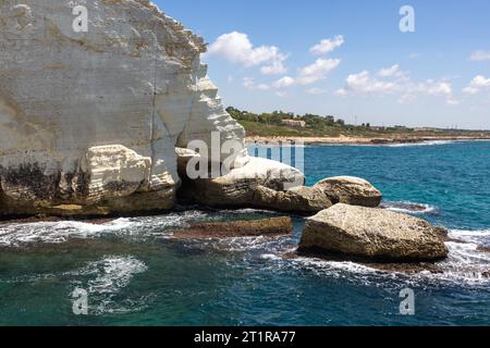 Falaise blanche et rochers plongeant la mer à Rosh Hanikra, au nord d'Israël. Ciel bleu et quelques terres en arrière-plan. Banque D'Images