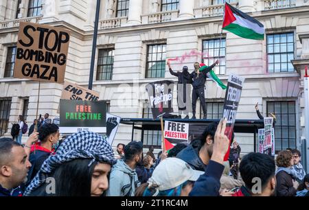 Londres, Royaume-Uni. 14 octobre 2023 : des manifestants pro-palestiniens se tiennent debout dans un abri de bus tenant une fusée éclairante rouge et un drapeau palestinien en signe de protestation en faveur de Palesti Banque D'Images