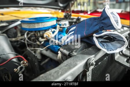 Gants de protection posés à côté du compartiment moteur de voiture classique pendant le processus de restauration de voiture. Banque D'Images