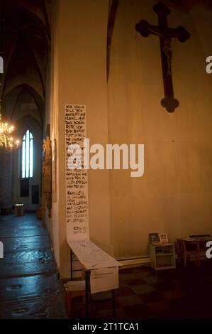 Flensburg, Schleswig-Holstein Unterschriftenaktion in der St. Nikolai Kirche, Flensburg. An der Wand ein weiße Zeichenpapierrolle mit texte : ICH verurteile den Angriff auf Israel auf das Schärfste. ICH bin entsetzt über die unfassbaren Gräueltaten. Mein Mitgefühl gilt allen jüdischen Opfern und deren Familien wie auch den zivilen Opfern und deren Familien im Gazastreifen. ICH versprèche, auf Vertrauen, Freundschaft und Gespräche zu setzen. Rechts an der Wand ein Jesus Kreuz. Aufnahme vom 15.10.2023, Flensburg, *** Flensburg, Schleswig Holstein campagne de signature dans l'église St Nikolai, Flensburg Banque D'Images