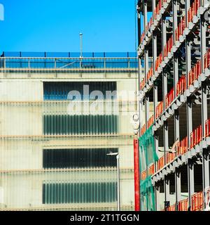 Nouveau cadre en acier du bâtiment fixé contre le parking de plusieurs étages terminé Banque D'Images