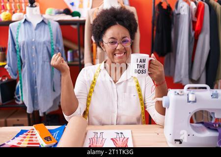 Belle femme africaine avec couturière frisée de cheveux buvant de je suis la tasse de patron criant fier, célébrant la victoire et le succès très exci Banque D'Images