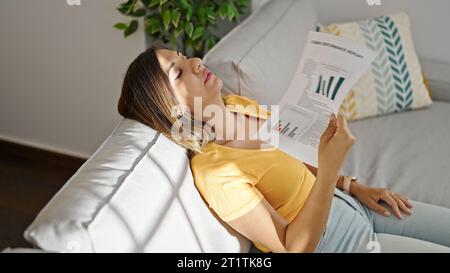 Femme du Moyen-Orient faire de l'air avec des papiers transpirant à la maison Banque D'Images