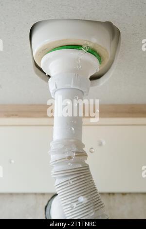 Fuites d'eau à la maison dans la salle de bain. L'eau s'écoule du tuyau sous l'évier Banque D'Images