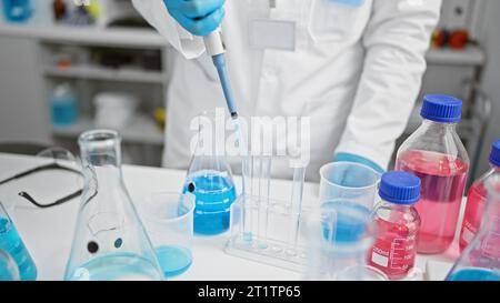 Jeune homme hispanique passionné, un scientifique séduisant aux cheveux gris, versant méticuleusement du liquide dans un tube à essai, perdu dans ses recherches à une la bourdonnante Banque D'Images