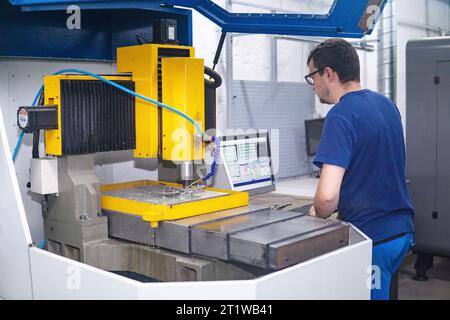 Perm, Russie - 13 juillet 2023 : travailleur dans l'atelier régule le fonctionnement d'une machine à travailler les métaux Banque D'Images