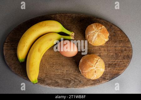 branche de bananes se trouve sur la table avec des œufs et des pains à hamburger. aplatissement Banque D'Images