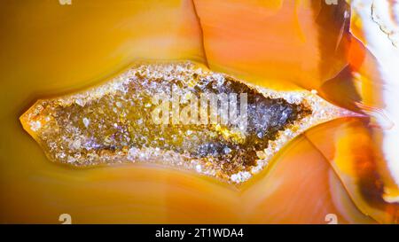 Petite géode avec des cristaux de quartz à l'intérieur du détail de la section transversale de la pierre précieuse d'agate. Belle cavité en gemme taillée avec surface polie jaune or ou orange. Banque D'Images