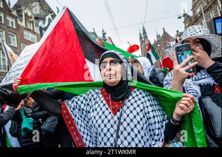 Amsterdam, pays-Bas. 15 octobre 2023. Une femme palestinienne âgée marche avec un drapeau palestinien lors d'une manifestation de solidarité avec la Palestine. La communauté palestinienne aux pays-Bas a organisé une marche dans le centre de la ville pour condamner le gouvernement israélien et exprimer sa solidarité avec le peuple palestinien. Crédit : SOPA Images Limited/Alamy Live News Banque D'Images