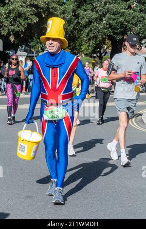 Great South Run, 15 octobre 2023, Portsmouth, Hampshire, Angleterre, ROYAUME-UNI. Des milliers de concurrents ont couru dans le 10 Mile Great South Run qui a commencé et s'est terminé à Southsea, Portsmouth. En plus des coureurs d'élite, beaucoup d'autres personnes ont participé à la course pour la charité ou pour leurs clubs. Sur la photo : un homme portant un costume de Union Jack collectant de l'argent pour l'organisme de bienfaisance Marie Curie Banque D'Images