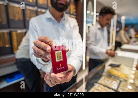 New Delhi, Inde. 15 octobre 2023. Un employé montrant la pièce d'or de 10 grammes aux clients, le jour du lancement de la nouvelle salle d'exposition de bijoux Kalyan à Karol Bagh, New Delhi, Inde. Kalyan Jewelers est une chaîne indienne de showrooms de bijoux. Il a été fondé par T. S. Kalyanaraman en 1993. Crédit : SOPA Images Limited/Alamy Live News Banque D'Images