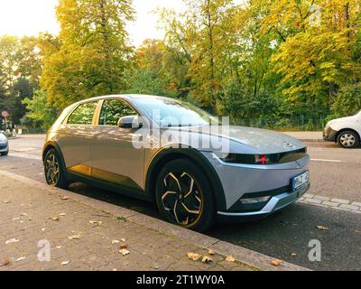 Paris, France - 10 octobre 2023 : IONIQ 5 by Hyundai, un véhicule électrique élégant, garé dans le centre-ville avec une finition métallique grise saisissante, entouré d'arbres verdoyants. Banque D'Images