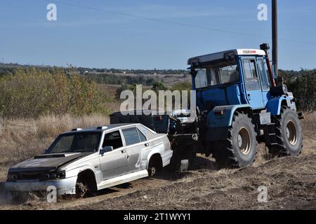 Une voiture endommagée avec la lettre “Z” (symbole de la guerre de la Russie en Ukraine vu sur le remorquage du tracteur à Velyka Oleksandrivka. En mars 2022, Velyka Oleksandrivka est occupée par les forces russes. Le 4 octobre 2022, les autorités ukrainiennes ont repris le contrôle de la colonie pendant la contre-offensive sud. Kyiv nord, Sumy, Tchernihiv, Mykolaïv sud, Zaporizhzhia, Kherson et les régions orientales de Kharkiv, Louhansk et Donetsk sont les plus minées, selon le Service d'urgence de l'Ukraine. Il faut au moins dix ans pour nettoyer ces zones. Banque D'Images