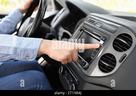 Sélection de la radio favorite. Femme appuyant sur le bouton sur l'audio du véhicule dans la voiture, gros plan Banque D'Images