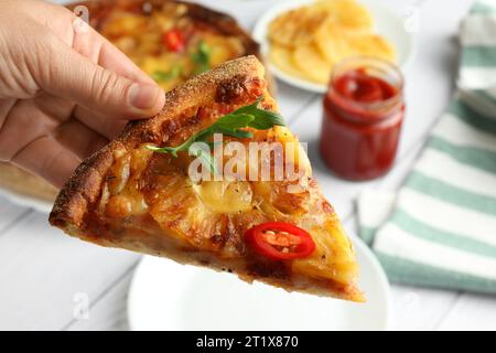 Femme tenant un morceau de délicieuse pizza hawaïenne avec de l'ananas, gros plan Banque D'Images