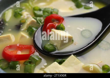 Bol de délicieuse soupe miso avec tofu et cuillère, gros plan Banque D'Images