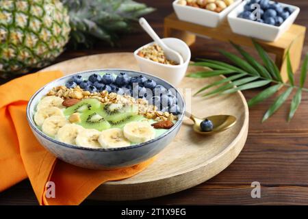 Savoureux bol à smoothie avec des fruits frais et des flocons d'avoine servis sur une table en bois Banque D'Images