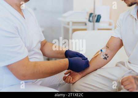 Médecin expert administrant une thérapie vitale IV à un patient dans une chambre d'hôpital moderne. Des soins de qualité et des diagnostics précis fournis. Banque D'Images