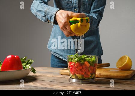 Femme méconnaissable utilisant la centrifugeuse manuelle pour presser le citron dans le bol du blender Banque D'Images