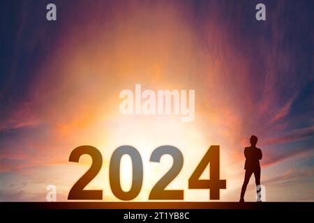 Stand d'homme d'affaires avec concept de nouvelle année 2024 et fond de lever du soleil Banque D'Images