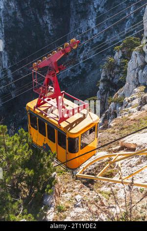 La cabine jaune d'un téléphérique monte à la montagne ai-Petri par une journée ensoleillée, photo verticale Banque D'Images