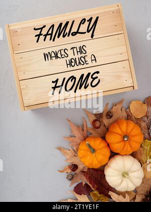 Famille fait de cette maison une citation à la maison sur une caisse en bois avec des citrouilles d'automne et des feuilles d'automne. Banque D'Images