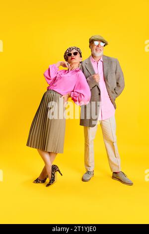 Mode élégant. Sénior élégant attrayant femme et homme dans les vêtements assortis posant sur fond de studio jaune Banque D'Images