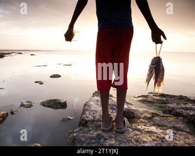 Un jeune garçon éthiopien tient son poisson frais sur les rives du lac Langano, Éthiopie. Banque D'Images