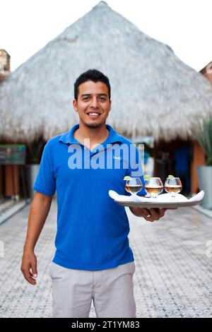 Un barman tient quatre tequilas sur un plateau dans un hôtel de Todos Santos, au Mexique. Banque D'Images