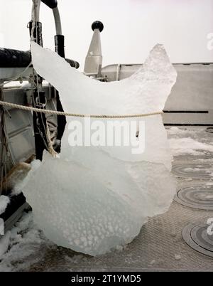 Une vis à glace dans un gros morceau de glace à l'avant d'un bateau couvert de neige dans les eaux de Prince William Sound, Alaska. Banque D'Images
