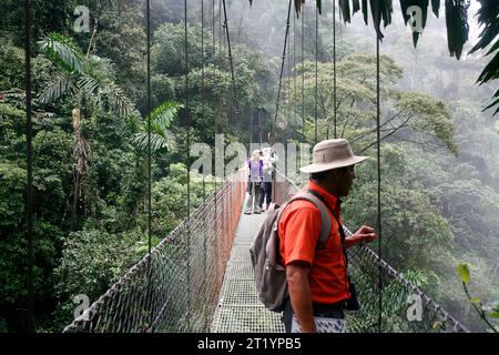 Randonneurs dans la réserve de forêt tropicale Arenal marchant sur un pont suspendu. Région de la Fortuna, Costa Rica. Banque D'Images