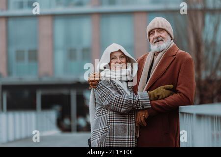 Élégant couple senior marchant près de la rivière, pendant la journée froide d'hiver. Banque D'Images