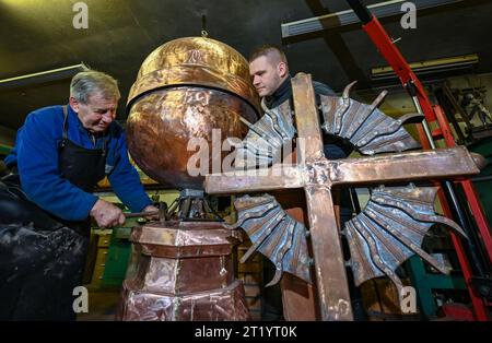 16 octobre 2023, Brandenburg, Angermünde : Maître métallurgiste Wilfried Schzuchow (l) travaille dans son atelier avec son fils Paul sur le couronnement de l'église du château de Berlin-Buch. Depuis plusieurs années, avec des interruptions de temps en temps, le maître métallurgiste Schzuchow travaille sur le couronnement de la Schlosskirche. Pour la sphère de cuivre seule, qui a été forgée à la main à partir de deux plaques, le forgeron de l'artiste a eu besoin de trois semaines. La sphère avec support et la croix sont en partie en acier et plaquées de cuivre. Début 2024, toutes les pièces seront dorées. L'église du château de Buch est située dans le Banque D'Images