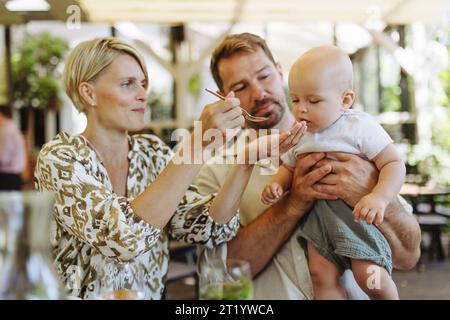 Parents dans le restaurant nourrissant petit bébé. Dîner familial au restaurant. Banque D'Images