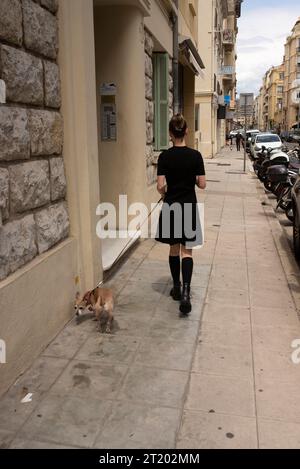 Fille en hautes bottes noires marchant loin tout en promenant le chien Banque D'Images