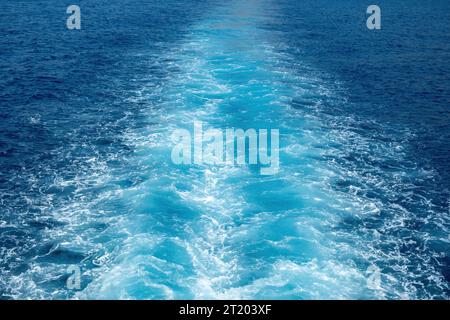 sillage blanc de bateau, mousse de lavage de prop sur la texture de fond de mer bleu. Éclaboussures d'eau profonde ondulée et ondulée derrière le navire. Espace Banque D'Images