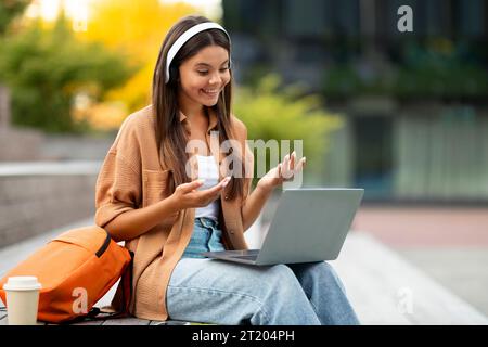Étudiant animé avec ordinateur portable et écouteurs dans un endroit tranquille de l'université Banque D'Images