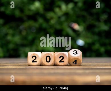 Bonne année 2024 avec commencer une nouvelle histoire, des tendances et des affaires. Concepts de durabilité environnementale. Retournement de 2023 à 2024 numéros sur cube en bois éco Banque D'Images