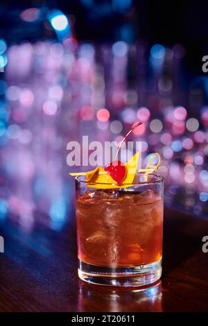 verre glacé sophistiqué de negroni garni de cerise avec fond de bar, concept Banque D'Images