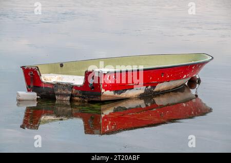 Un petit bateau de pêche rouge vieilli, abîmé, dans le lac suédois de Finjasjön, situé à l'extérieur de Hässleholm, Suède, projetant son reflet sur l'eau' Banque D'Images