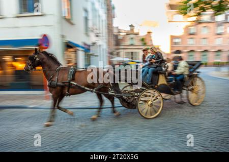 Bruges, Belgique, août 20 2014, touristes en visite guidée dans une calèche tirée par des chevaux, mouvement flou Banque D'Images